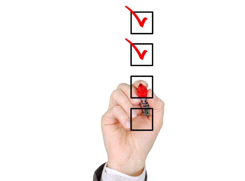 Hand setzt mit rotem Stift Häkchen auf einer Checkliste